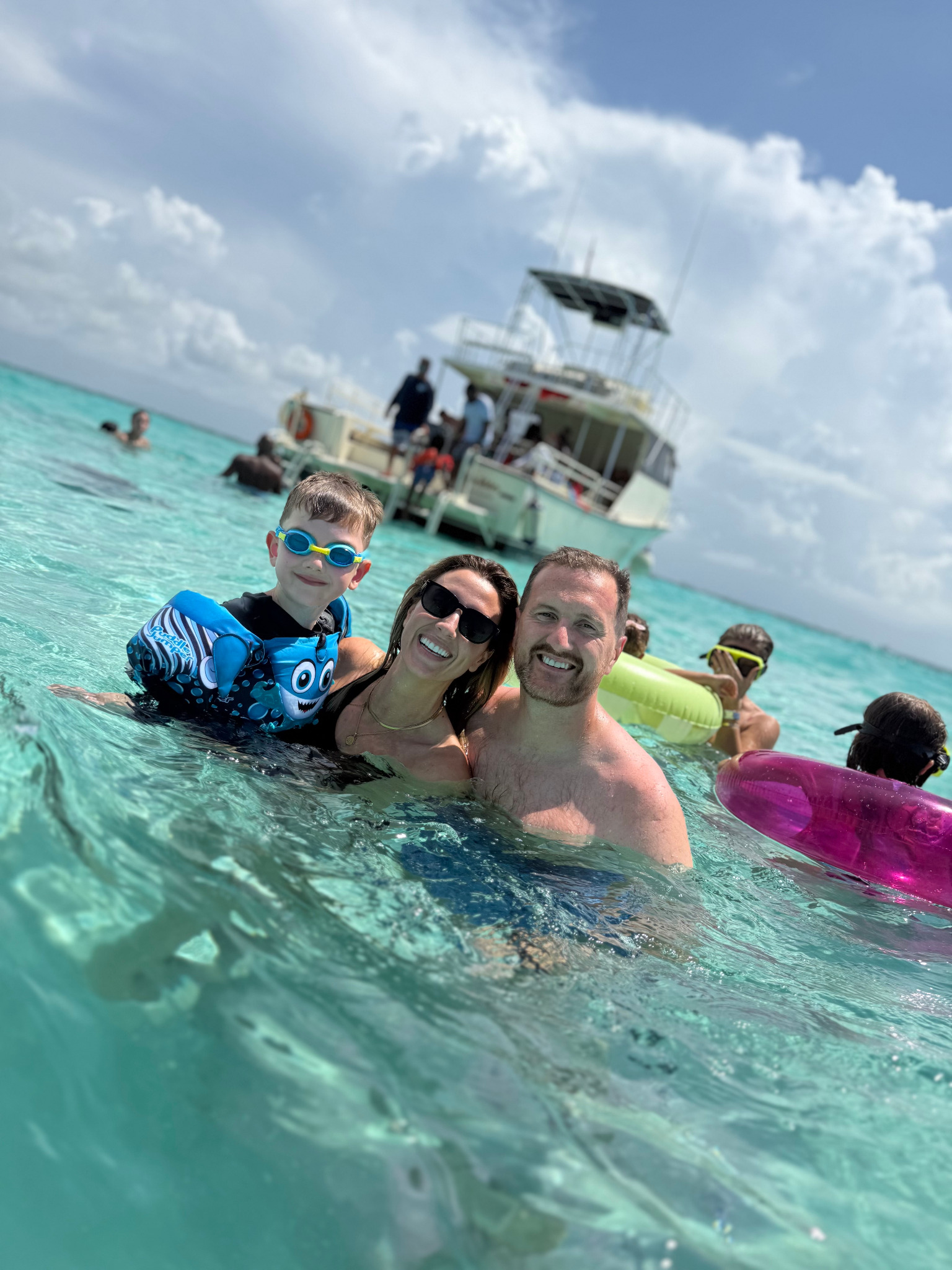 Family enjoying shallow turquoise water beside a DNS Diving boat in Grand Cayman.