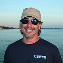 Dusty Norman, owner of DNS Diving, in a DNS Diving shirt on the water in Grand Cayman